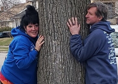 2 people hugging a tree wearing positive message shirts