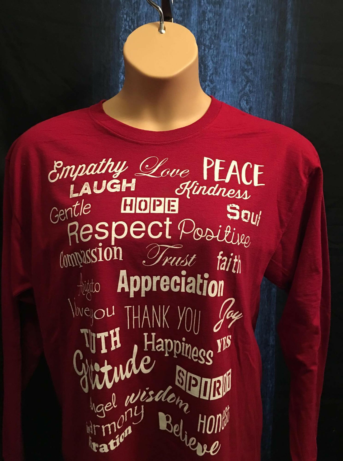 Close-up of high-quality red cotton-poly fabric and clean stitching on positive message long sleeve shirt