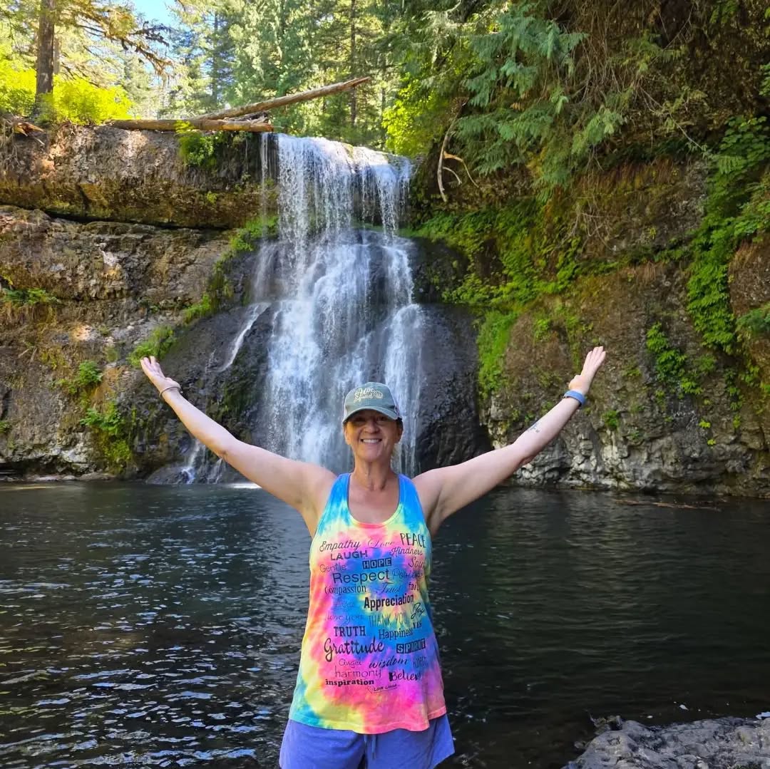Beautiful women wearing Love Lingo energy-based apparel tie die yoga tank in front of a waterfall