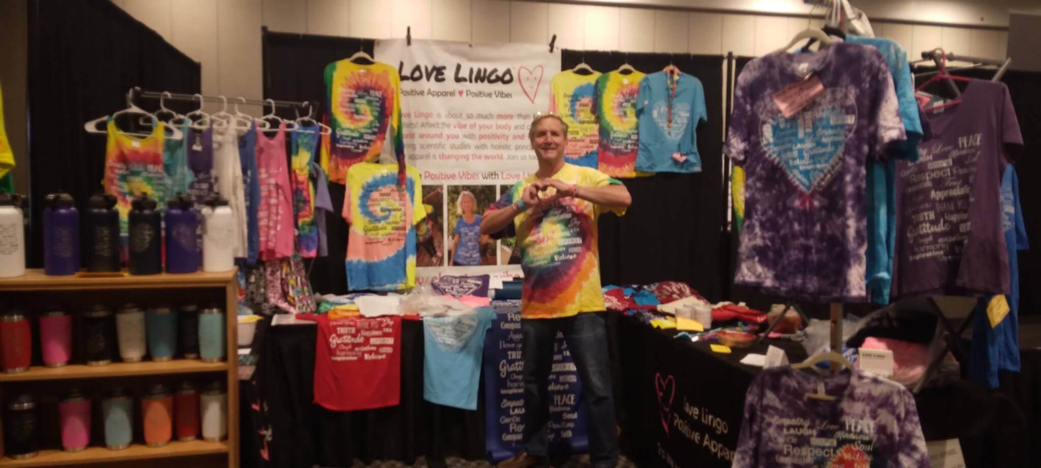 David setting up the Love Lingo booth at a holistic wellness expo, featuring high-vibration affirmation apparel